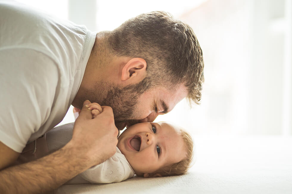 Young father kisses happy baby. 