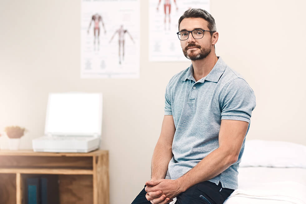 Portrait of a handsome mature male physiotherapist sitting in his office